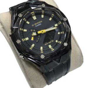 ساعة G-SHOCK CasiOak معدلة بإطار وكفة شفافة ومينا طيفي بألوان الطيف الأزرق والأرجواني (Rainbow Dial) على حامل عرض بيج.